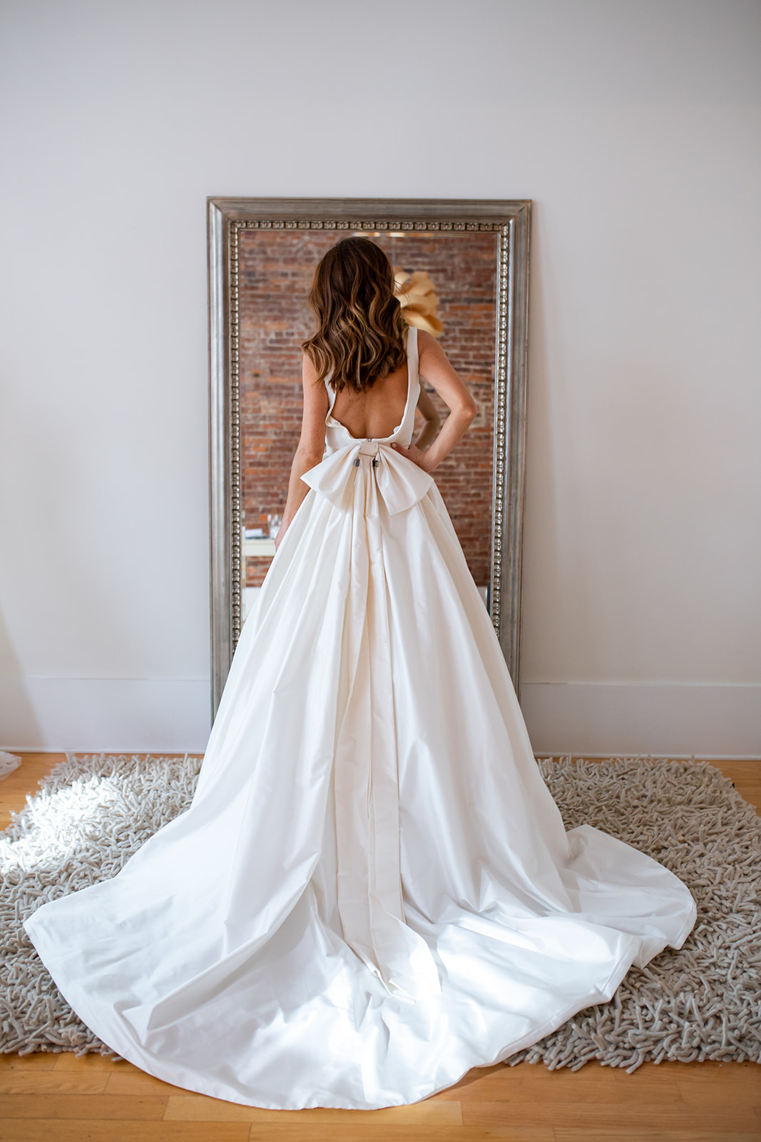 Sarah models gown with a dramatic back and bow at Modern Trousseau