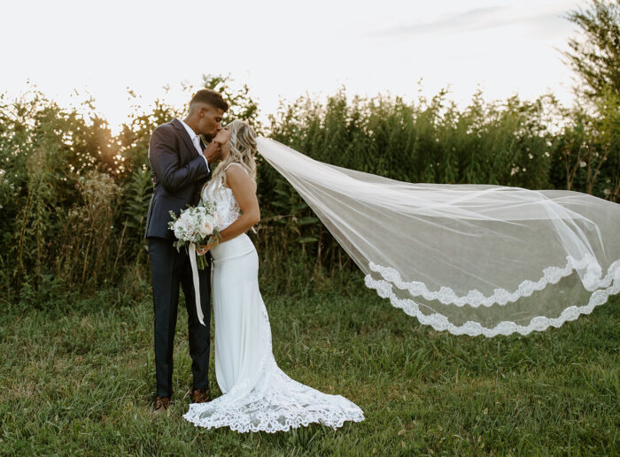 Bride and groom kiss in field